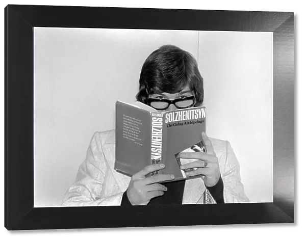 England footballer Malcolm MacDonald clowns around with glasses whilst reading '
