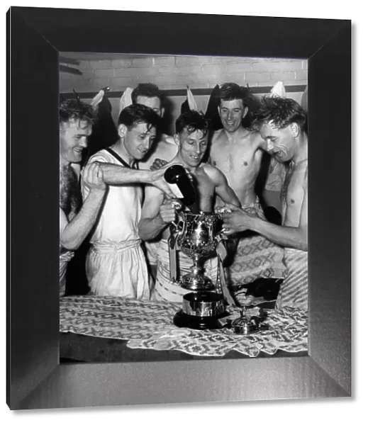Some of the team fill the Giant Killer Cup with champagne in the dressing room