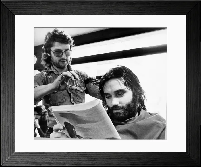 Framed Print : George Bests reads the paper whilst having his haircut May 1974 Framed Print : George Bests reads the paper whilst having his haircut May 1974
