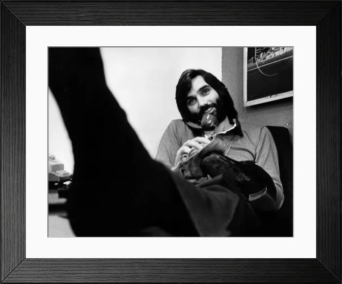 Framed Print : George Best in his office cleaning his shoes whilst chatting on the phone May 1974 Framed Print : George Best in his office cleaning his shoes whilst chatting on the phone May 1974