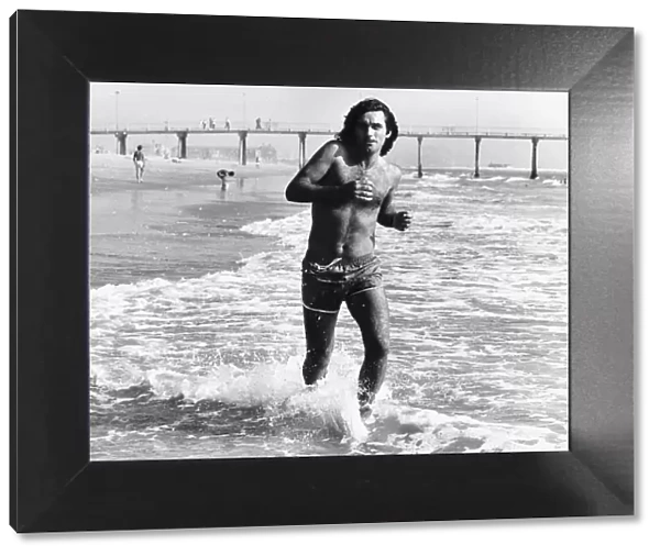 George Best football goes jogging on a beach in California