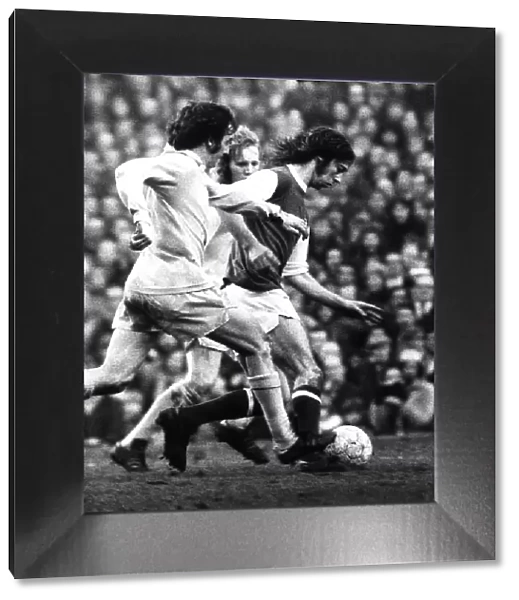Arsenal footballer Charlie George fights off 2 Bradford defenders as he makes an attack