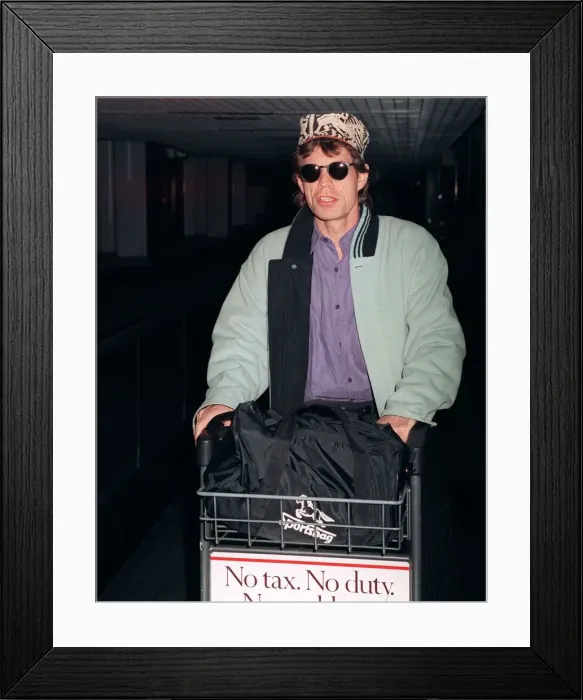 Framed Print : Rolling Stones: Mick Jagger arriving at Heathrow airport pushing trolley in February 1990