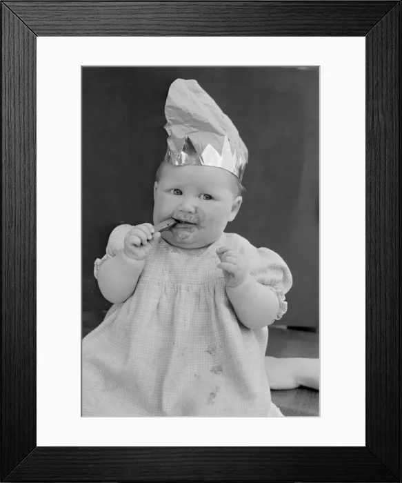Framed Print : Baby wearing a party hat and eating a cadbury chocolate finger 31st October 1952 Framed Print : Baby wearing a party hat and eating a cadbury chocolate finger 31st October 1952