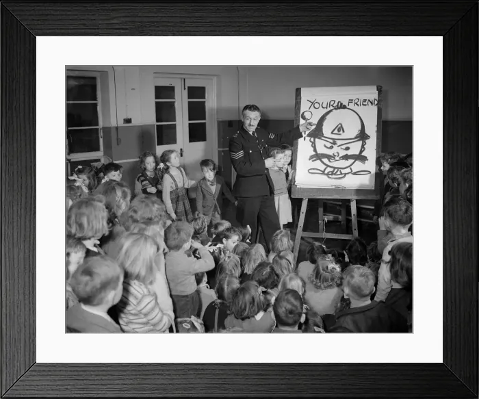 Framed Print : Children receiving a road safety lesson from a policeman during a class at school Framed Print : Children receiving a road safety lesson from a policeman during a class at school