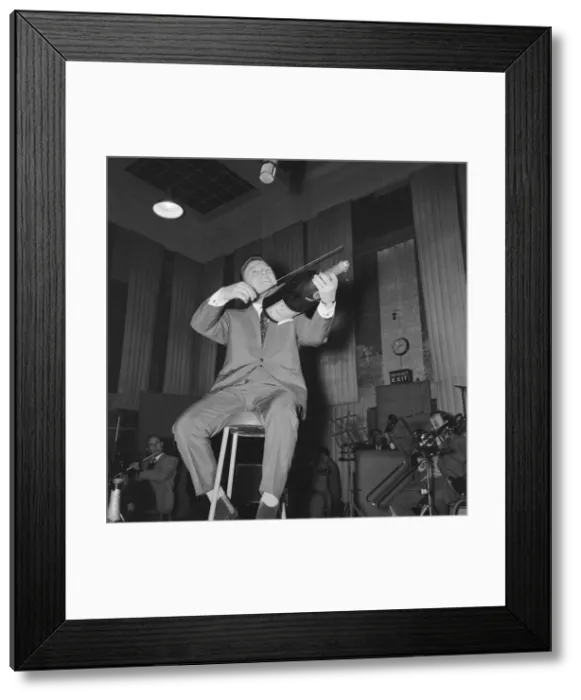Framed Print : English singer Matt Monro with a giant size bottle of champagne as he works on his latest