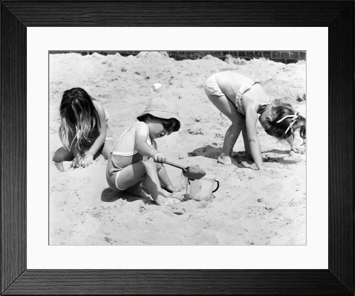 Framed Print : Young children playing in the sand, building sandcastles with a bucket