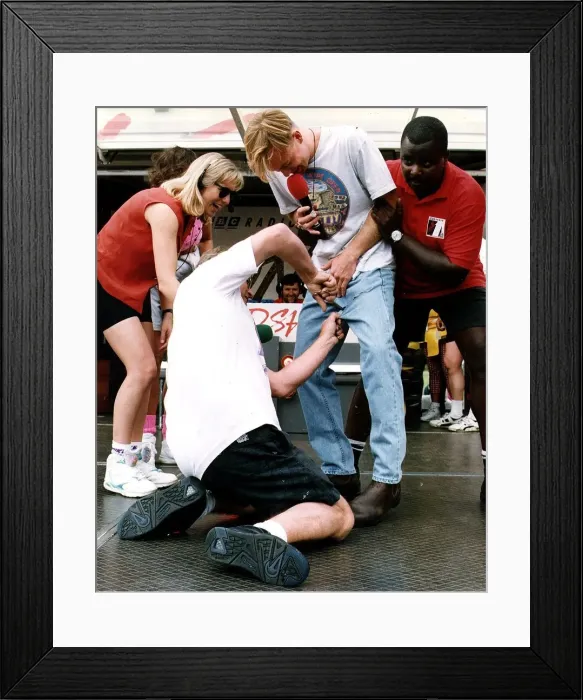 Framed Print : Jason Donovan Balloch Park Radio 1 roadshow being held from behind by black man while Framed Print : Jason Donovan Balloch Park Radio 1 roadshow being held from behind by black man while
