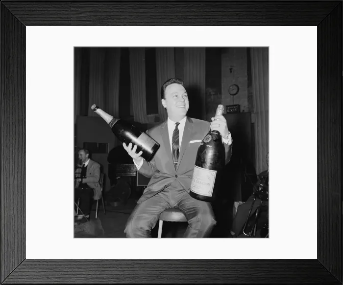 Framed Print : English singer Matt Monro with a giant size bottle of champagne as he works on his latest Framed Print : English singer Matt Monro with a giant size bottle of champagne as he works on his latest
