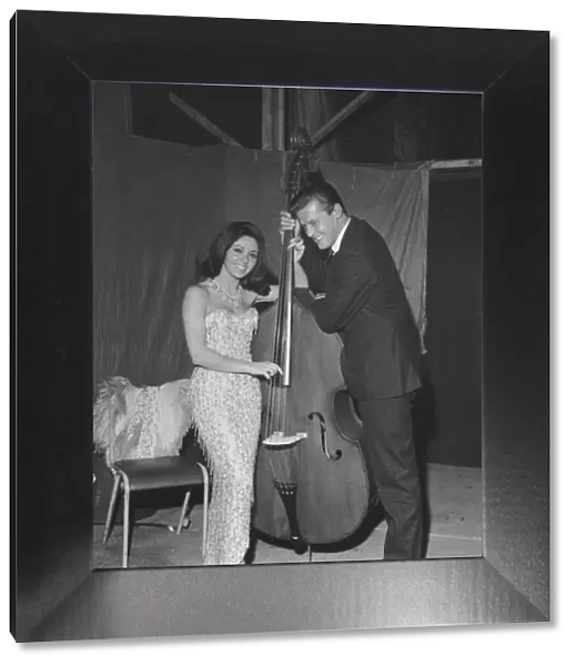 Pop singer Susan Maughan and actor Roger Moore photographed with a cello backstage during
