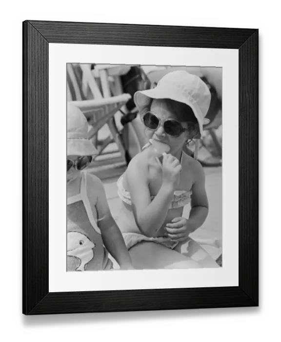 Framed Print : A young girl sitting on the beach, enjoying an ice lolly. 26th June 1979 Framed Print : A young girl sitting on the beach, enjoying an ice lolly. 26th June 1979