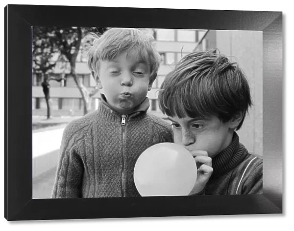 Eight year old Joseph Clifford of Hackney blows up his balloon as his younger brother