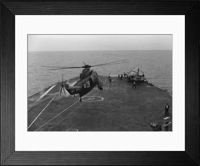 Framed Print : A Royal Navy Westland Sea King hovers over the deck as a Buccaneer with folded wings sits