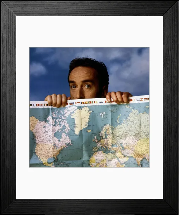 Framed Print : Angus Deayton TV presenter peering looking over map of the world Framed Print : Angus Deayton TV presenter peering looking over map of the world