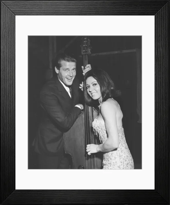 Framed Print : Pop singer Susan Maughan and actor Roger Moore photographed with a cello backstage during