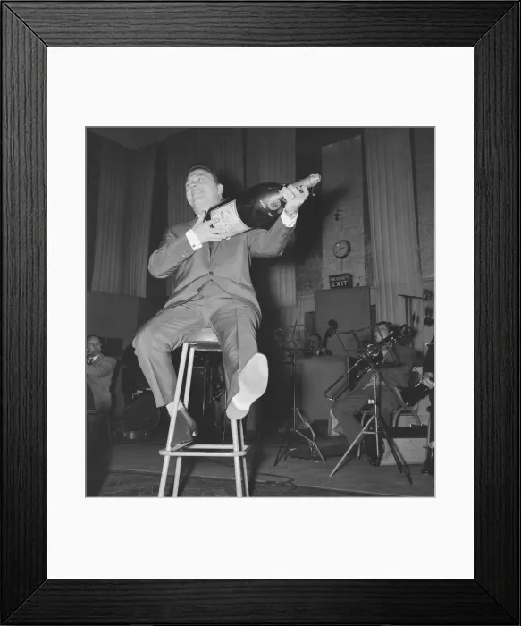 Framed Print : English singer Matt Monro with a giant size bottle of champagne as he works on his latest Framed Print : English singer Matt Monro with a giant size bottle of champagne as he works on his latest