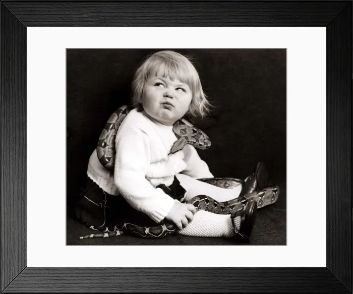Framed Print : Young girl with a snake wrapped around her pulling a funny face Circa 1960 Framed Print : Young girl with a snake wrapped around her pulling a funny face Circa 1960