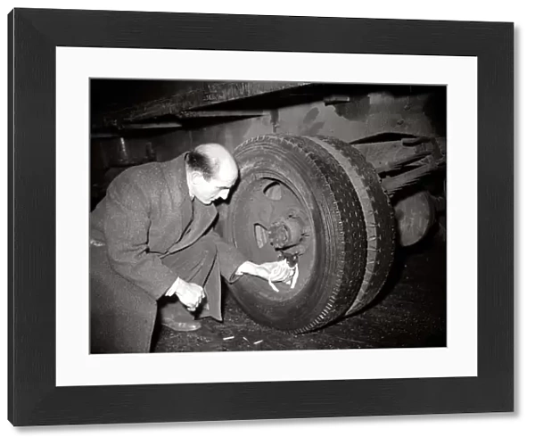 A man helps a kitten who was trapped in lorry wheel January 1950