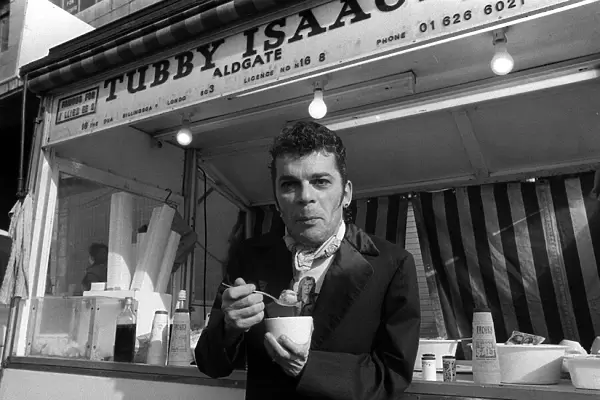 Ian Dury outside the East End stall of Tubby Isaacs eating bowl of Jellied eels