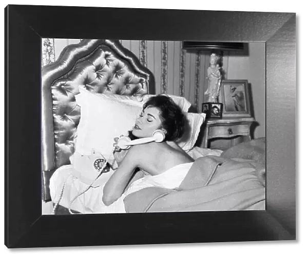 Actress Jackie Lane lying in bed naked talking on the telephone March 1959