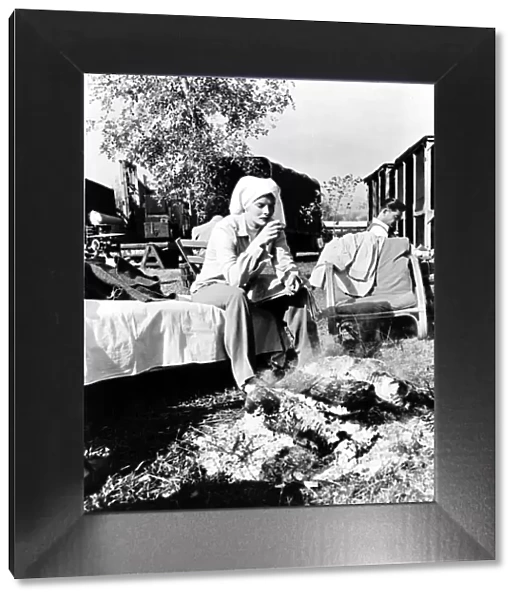 Katharine Hepburn wearing a towel around head sitting by an open fire drinking coffee