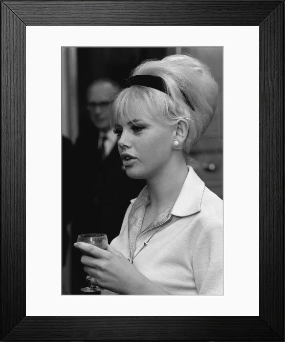 Framed Print : Actress Britt Ekland holding a wine glass, deep in conversation. circa 1960s
