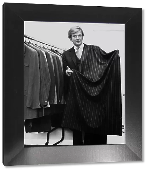 Roger Moore actor holding a length of suiting cloth October 1970 he is a director of