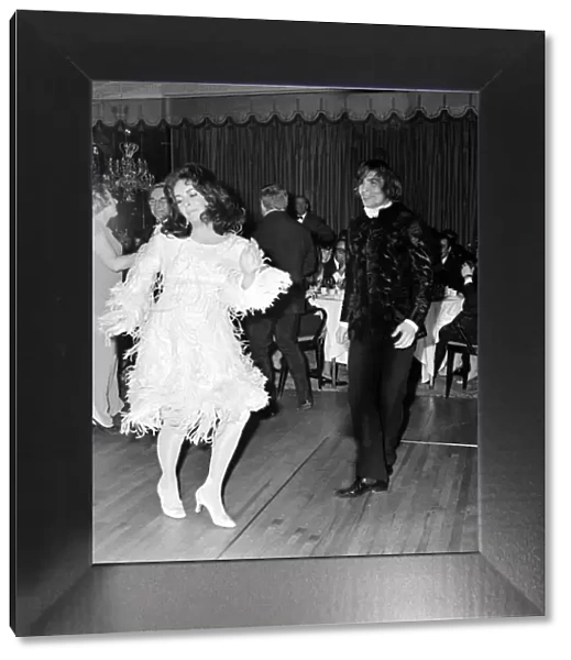 Actress Elizabeth Taylor dancing with Nureyev wearing an unusual feathered dress