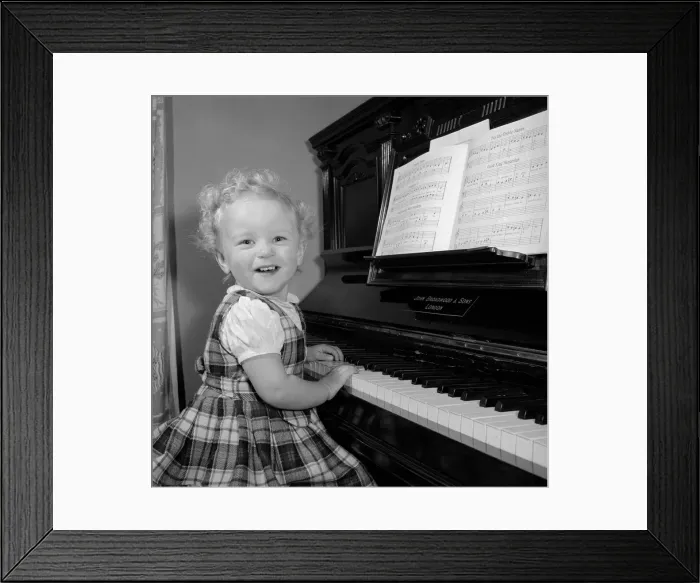 Framed Print : A small girl plays the piano Circa 1957 Framed Print : A small girl plays the piano Circa 1957