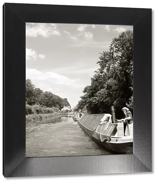 Woman on canal boat in the sun whilst child sunbathes behind her - circa 1950