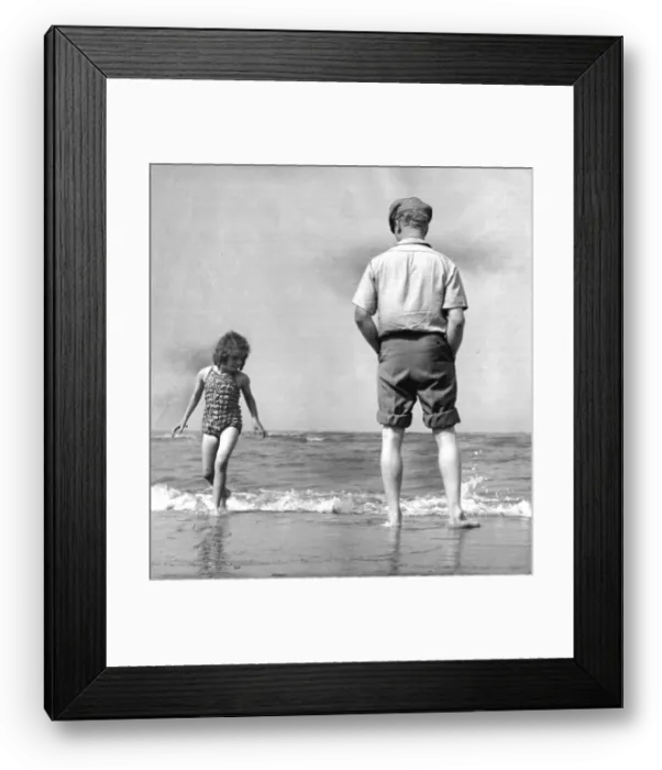 Framed Print : The picture shows a father or grandfather with a little girl on the beach Framed Print : The picture shows a father or grandfather with a little girl on the beach