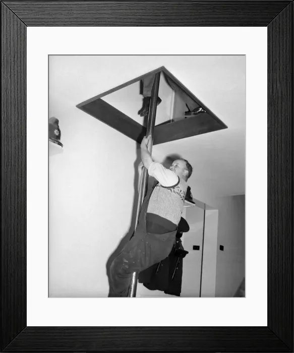 Framed Print : Part time fireman in action, sliding down firemans pole to answer an emergency call