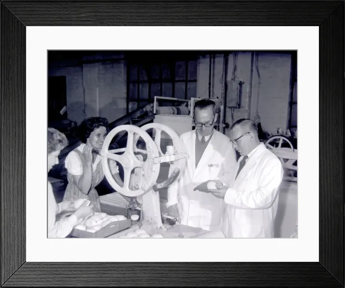 Framed Print : Checking soap as it comes warm from the moulding machine that stamps it into distinctive Framed Print : Checking soap as it comes warm from the moulding machine that stamps it into distinctive