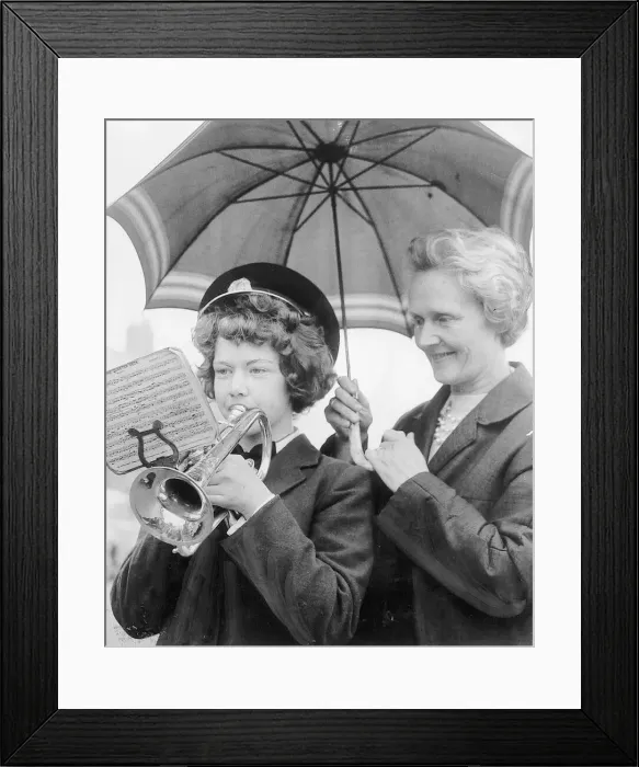 Framed Print : Christine Blythe, aged 13, a cornet player from Dudley, gets protection from the rain as Framed Print : Christine Blythe, aged 13, a cornet player from Dudley, gets protection from the rain as