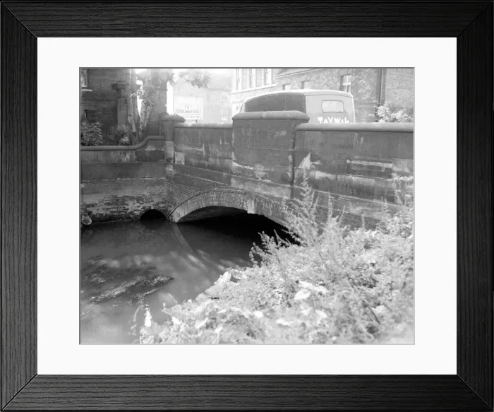 Framed Print : Driftwood floating on the river. Vans crossing over the bridge on their way towards Framed Print : Driftwood floating on the river. Vans crossing over the bridge on their way towards