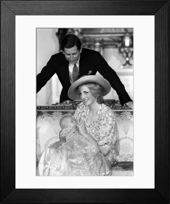 Framed Print : Princess Diana, watched by husband prince Charles, holds her son Prince William in her Framed Print : Princess Diana, watched by husband prince Charles, holds her son Prince William in her