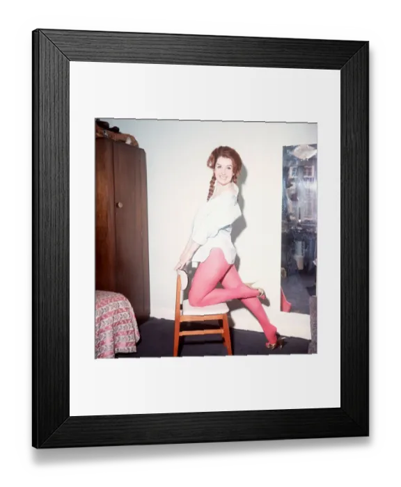 Framed Print : Heller Toren model actress 1964 knee on chair holding back pink tights white shirt
