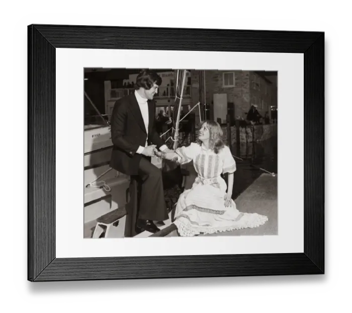 Framed Print : Man wearing a navy blue blazer white polo sweater and trousers helps a lady out of a boat