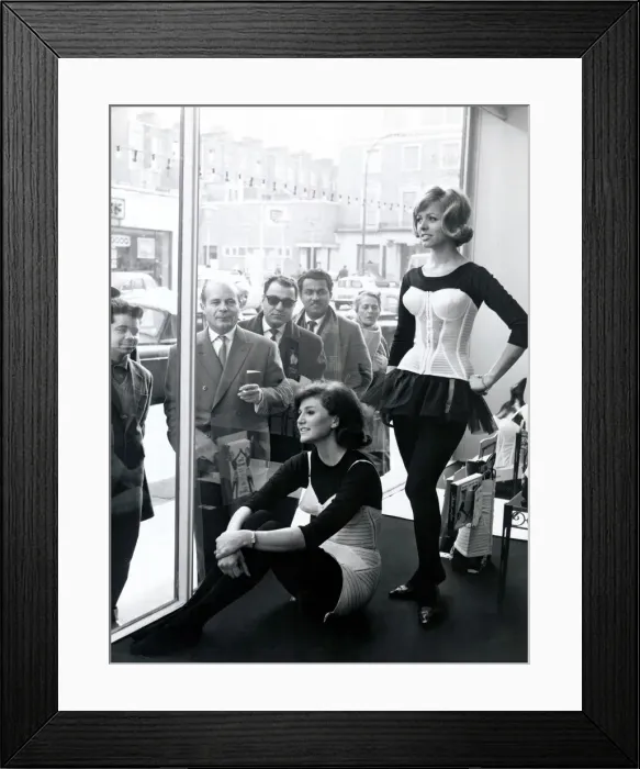 Framed Print : Two women modelling corsets in shop window while people on the street look in - March Framed Print : Two women modelling corsets in shop window while people on the street look in - March