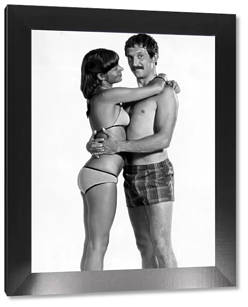 A man wearing checked shorts embracing a woman wearing a bikini August 1976
