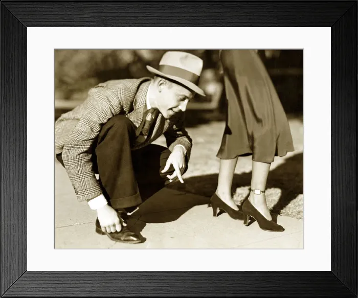 Framed Print : A Man wearing a tweed jacket, trousers and a trilby hat bends over to check the time on a