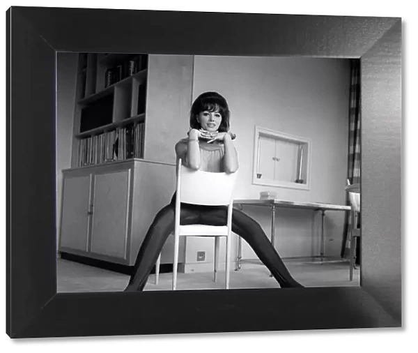 Jackie Collins authoress sitting astride a chair at home Mar 1964