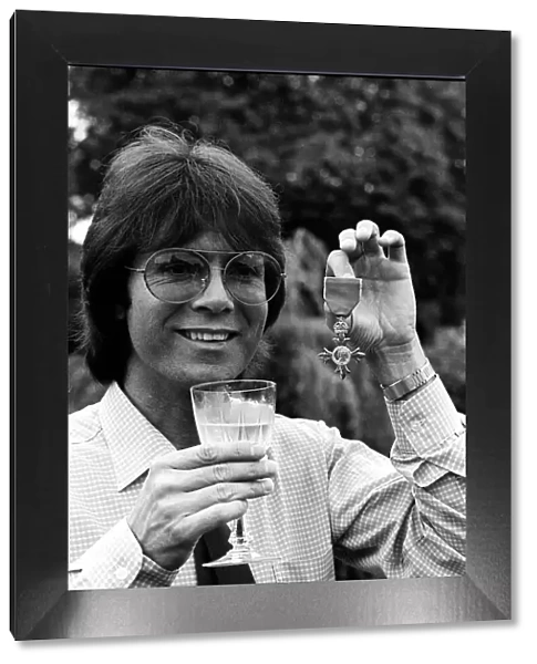 Cliff Richard with his OBE medal award drinkng wine 1980