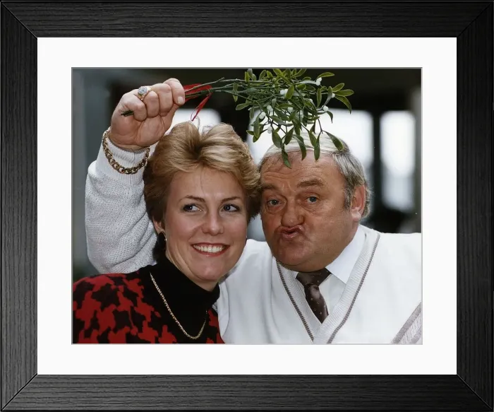 Framed Print : Jill Dando TV Presenter with Les Dawson who is holding mistletoe over their heads Framed Print : Jill Dando TV Presenter with Les Dawson who is holding mistletoe over their heads