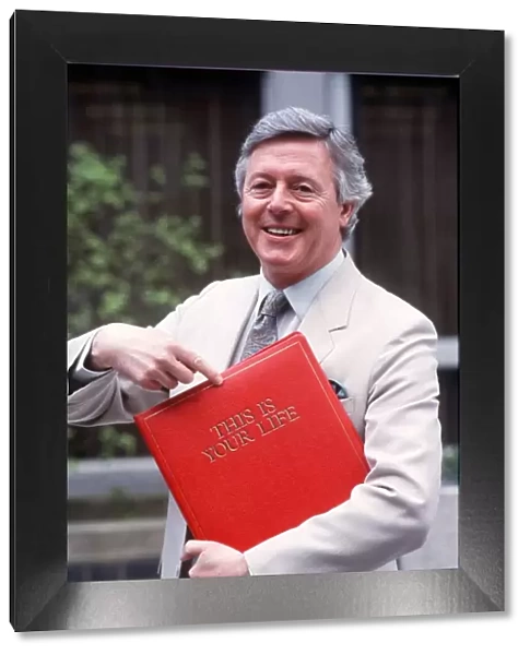 Michael Aspel TV Presenter of this is your life holding red book