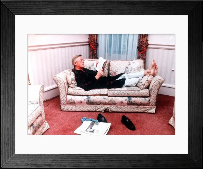 Framed Print : Michael Aspel TV Presenter of This is your Life lying on sofa reading book Framed Print : Michael Aspel TV Presenter of This is your Life lying on sofa reading book