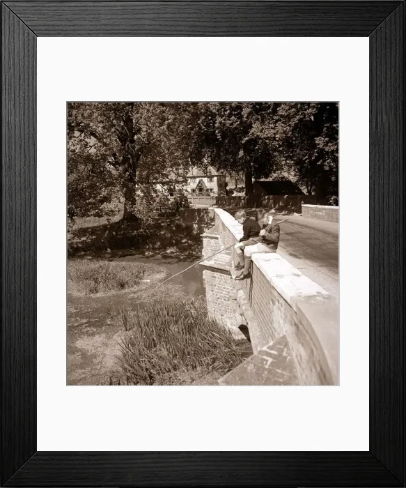 Framed Print : Two young boys sitting on the side of a bridge as they try fishing in their local river Framed Print : Two young boys sitting on the side of a bridge as they try fishing in their local river
