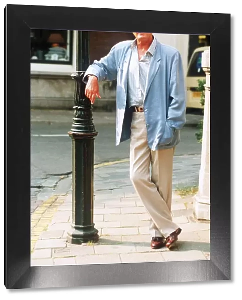 Roger Moore actor leaning against lamp post