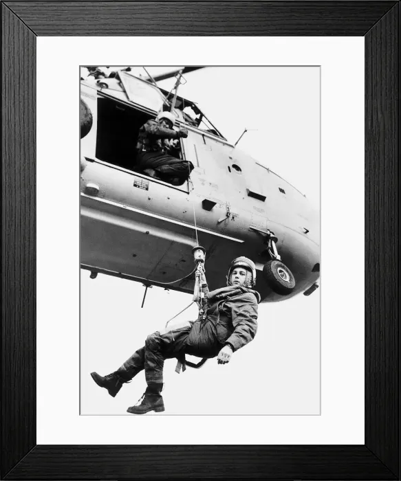 Framed Print : A Coastal Guards is lowered down from a helicopter on a winch to come to someone