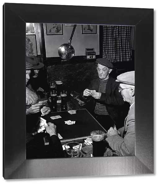 Fisherman around the table playing cards in a pub in St Ives in Cornwall February